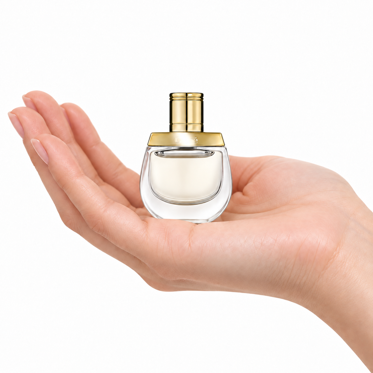 Golden Reverie 5ml miniature resting in a palm on white